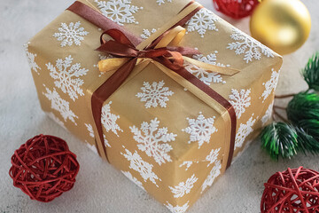 Christmas and New Year concept. A gift in a beautiful package and golden and red  balls on a gray background.