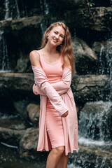 Young woman in pink dress  posing near blurred waterfall. Kuala Lumpur. Malaysia