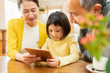 タブレット学習をする孫を見守る祖父母