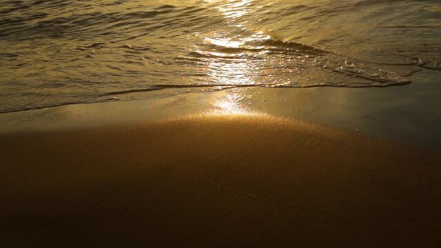 Peaceful waves rolling over smooth wet sand during the sunset -close up