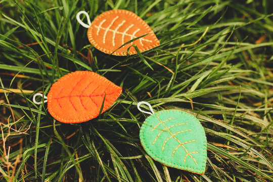 Leaves of different colors on the grass. Handmade autumn leaves. Felt leaves. Red leaf. Orange leaf