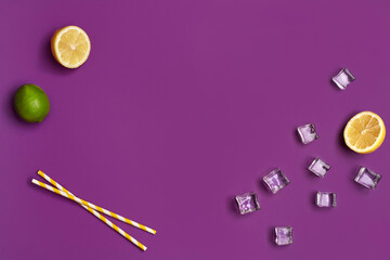 Whole green lime, two halves of  lemon, ice cubes and yellow tubules on purple studio background. Close up, copy space