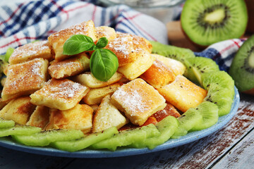 Austrian dessert Kaiserschmarrn served with sugar powder and kiwi fruit	