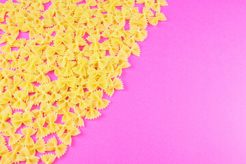 farfalle spread out in the corner on a bright pink background. Pasta pattern.
