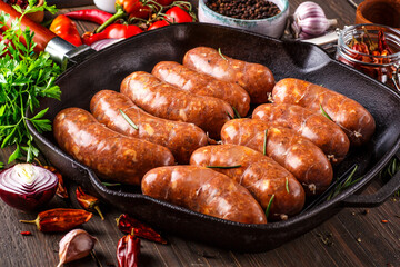 Grilled sausages, homemade,cast iron skillet or frying pan with tomatoes, garlic and rosemary. Brazilian barbecue. copy space