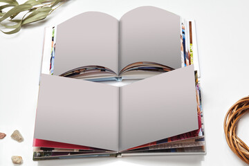 Two open high quality photo books with hardback and blank pages, green twig and small stones...