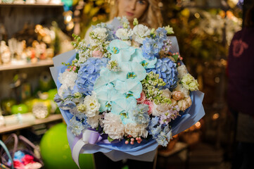 lovely floral bouquet with different flowers wrapped in paper in hands of pretty smiling woman