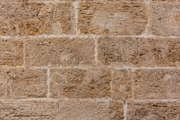 Old textured yellow stone block wall creating a pattern. Background for designs or advertising