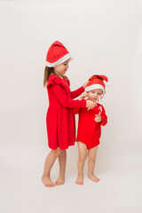 a little girl and a full-length boy in red caps with lollipops on a white background with a copy of space