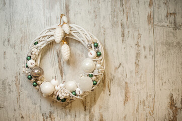 Beautiful wicker Christmas wreath decorated with white and blue balls, pine cones and berries.