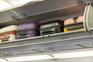 Carry-on luggage on the top shelf over head on airplane, passenger put bag cabin compartment air craft business class,vintage color,copy space © Semachkovsky 