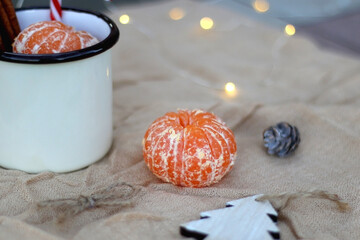 Peeled tangerine and Christmas decorations. Selective focus, bokeh lights.
