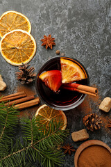 Glass of mulled wine and ingredients on black smokey background