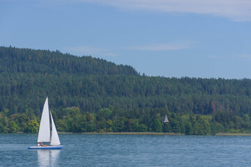 Obraz premium Boating and sailing on the clear waters of alpine Lake Worthersee, famous tourist attraction for many water activity, in Carinthia region, Austria