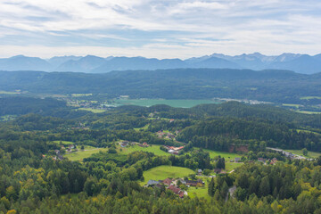Fototapeta na wymiar Charming village surrounded by mountains, view from The Pyramidenkogel, the highest wooden viewing tower in the world, famous tourists attraction at the lake Worthersee, Carinthia region, Austria