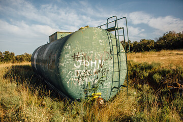 Obraz premium An old large possible water tank on the side of the field. The tank is described by various inscriptions