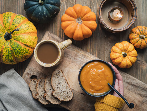 Pumpking sould with various little pumpkins on a rustic wooden table.