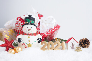 christmas card with snowman, gift box and number 2021 on the snow. copy space..