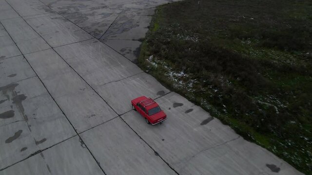 Red car on empty concrete road at cloudy autumn day