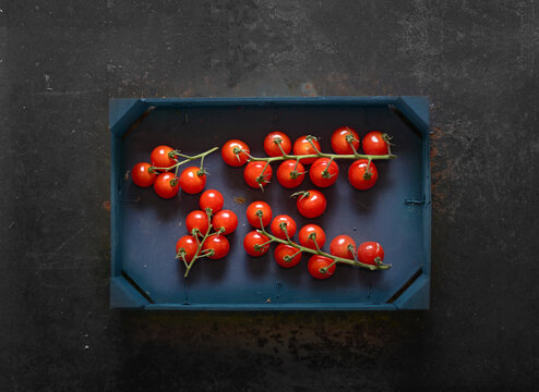 Cherry tomatoes on vines in a wooden crate