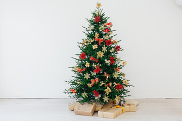 christmas tree with colorful balls and gift boxes over white wall