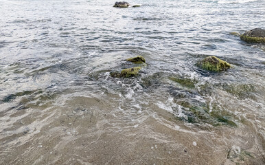 Beach on the sea with waves and stones in water