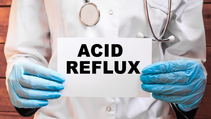 The doctor's blue - gloved hands show the word ACID REFLUX - . a gloved hand on a white background. Medical concept. the medicine