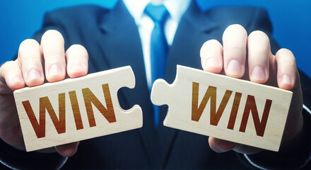 Man holding two puzzles with Win-Win words. A negotiation strategy makes all parties succeed....