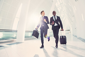 Smiling businessmen running to catch a flight in an airport