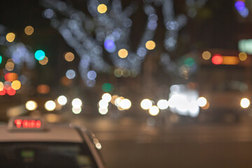 The big taxi sign on the blurred background of night city. Taxi driving at high speed through the heavy traffic at night.