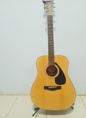 Naklejka premium Acoustic guitar coloured yellow on the background white