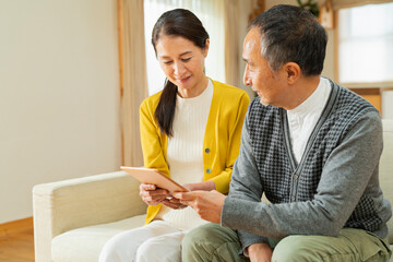 リビングでタブレット端末を使う老夫婦