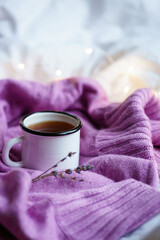 Fototapeta na wymiar purple knitted sweater, white cup of tea and lavender sprigs. the concept of tranquility, warmth and comfort. hygge at home