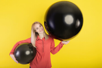 girl posing with two giant balloons on a yellow background