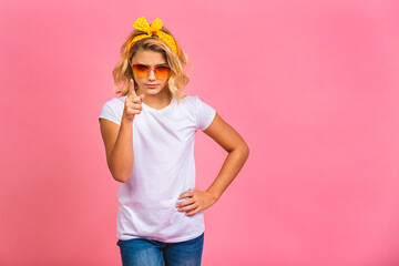 Smiling little kid girl 12-13 years old in casual isolated on pink background children studio portrait. Childhood lifestyle concept. Mock up copy space. Pointing finger.