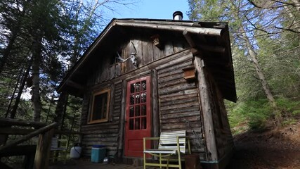 Camera moving from below towards the porch of mini house in the woodlands with colored red door. Cozy nest for adventurous living lovers.