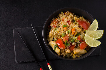 Khao Pad, fried rice with vegetables, meat and eggs, with fresh cucumbers, tomatoes, with chopsticks.