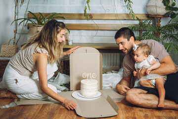 Happy family celebrating first birthday of baby daughter with cake. 1st Birthday home party ideas...