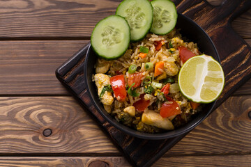 Asian khao pad kung fried rice with vegetables, meat, egg, fresh cucumbers and tomatoes
