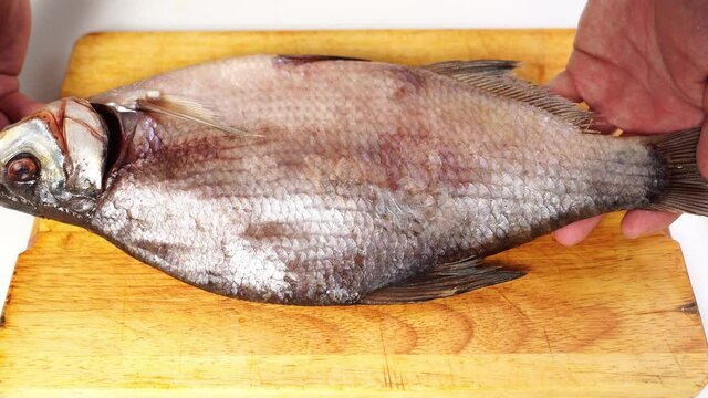 men's hands turn over dried salted bream on a wooden chopping Board. salted fish. traditional beer appetizer.