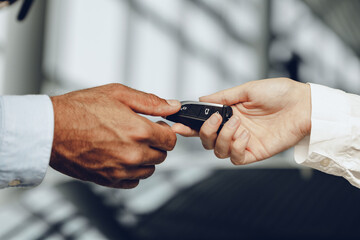 Car salesperson giving keys to a client close up