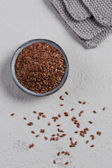 Brown flax seed or linseed in small bowl on light gray background.