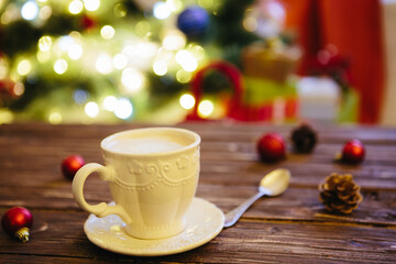 Mug with hot chocolate on a wooden table with Christmas decorations on a background of the Christmas tree