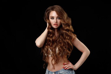 Naklejka premium Beauty portrait of elegant young woman. Glamour makeup. Face of the beautiful woman with long brown curly hair posing at studio over dark background. Sensual portrait.