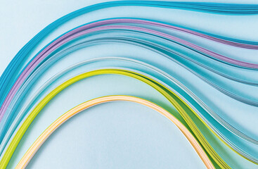 top view of multicolored wavy paper stripes for kwilling on blue background for text or logo