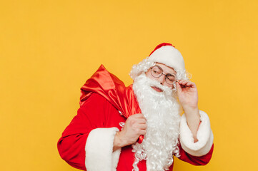 Concerned Santa Claus is touching his goggles and looking at his red sack with gifts, feeling confused and suspicious.