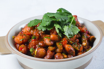 Stewed broad beans in tomato sauce with herbs and spices close-up,