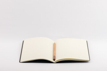 Closeup shot of an open blank book with pencil on a white background