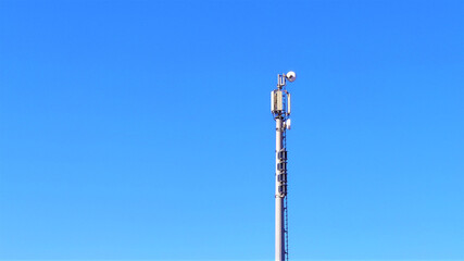 Telecommunication tower with antennas against blue sky background with copy space.