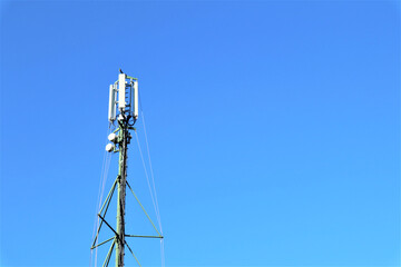 Telecommunication tower with antennas against blue sky background with copy space.